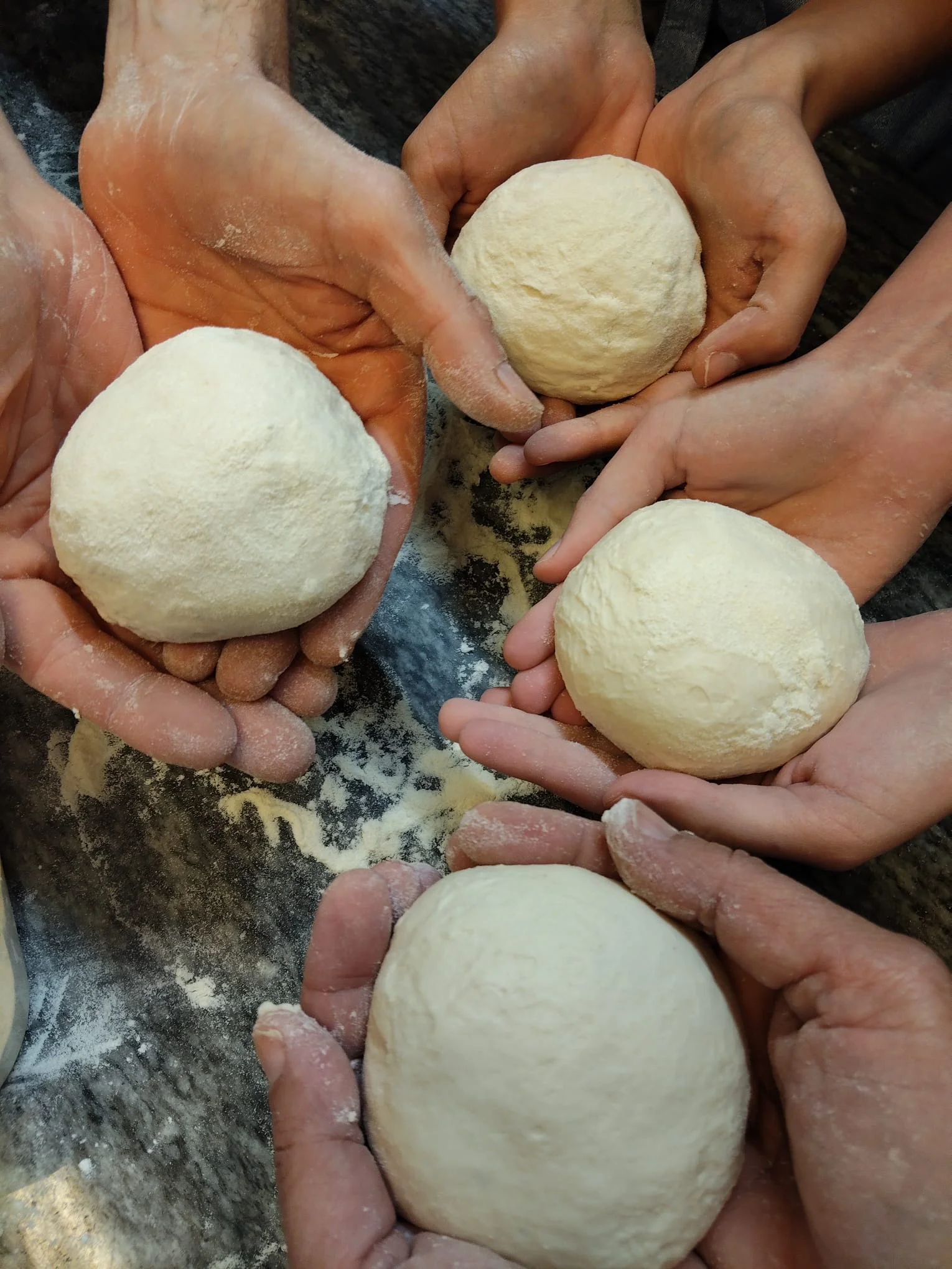 Mani degli allievi che mostrano le palline di pasta fresca preparate insieme durante il corso