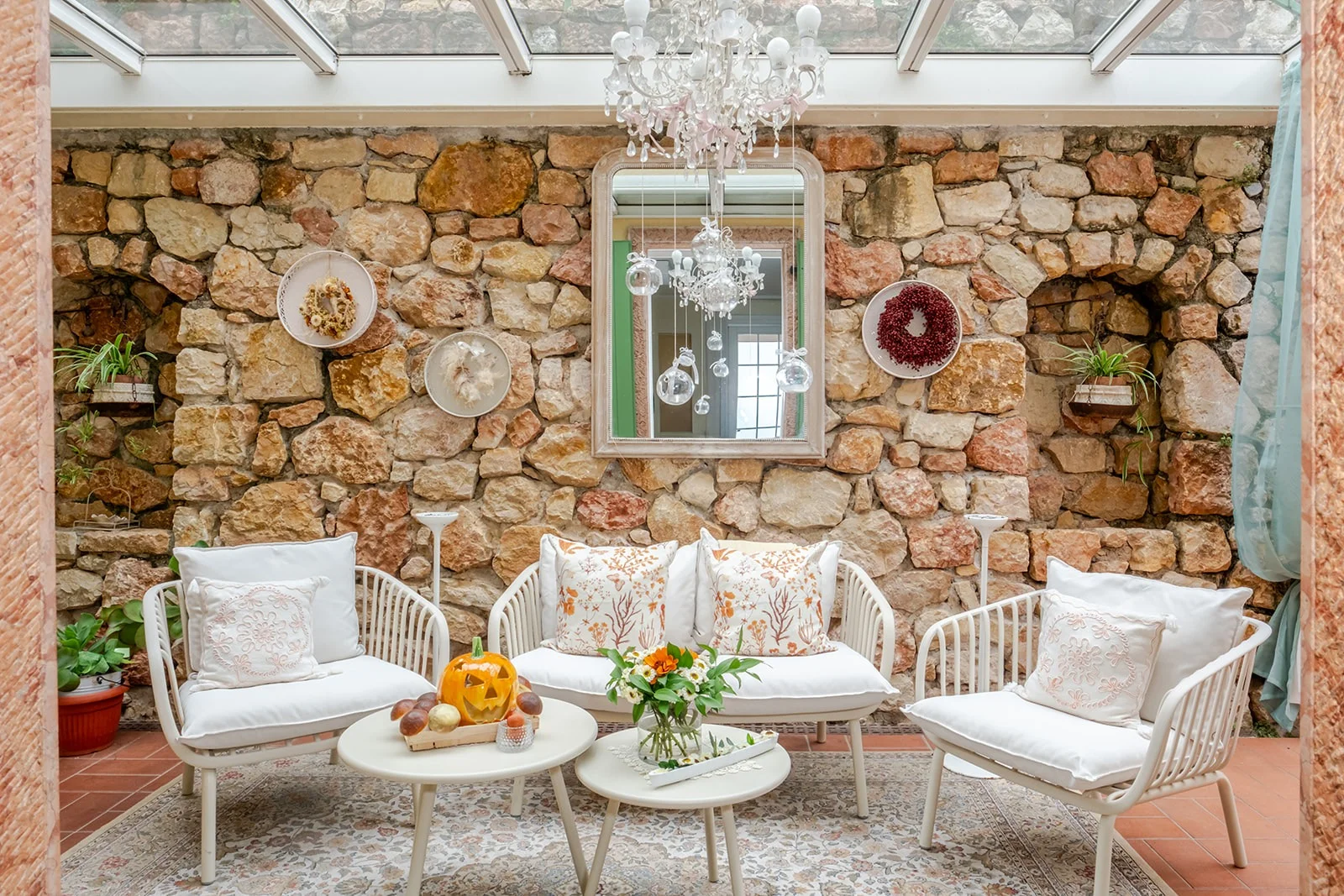 Il salotto-veranda di Le Gemme di Artemisia: muro in pietra, divani, lampadario, decorazioni