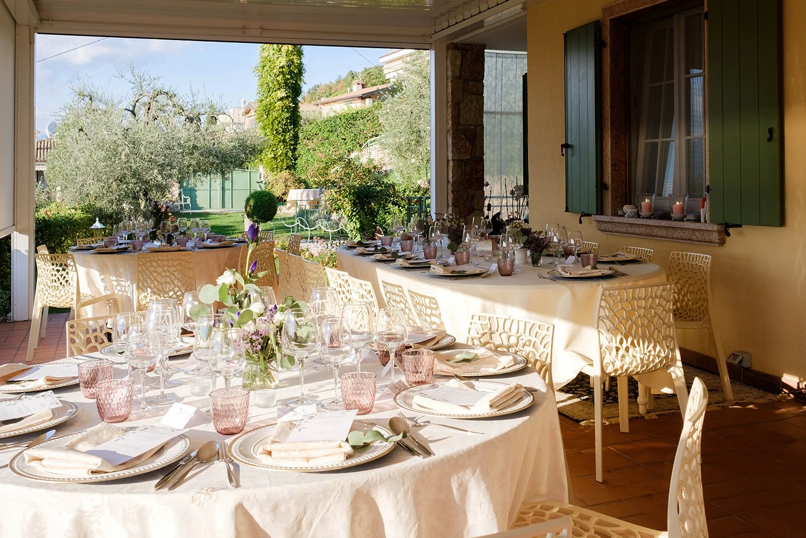 Banchetto matrimoniale con tavoli apparecchiati nella veranda con vista giardino