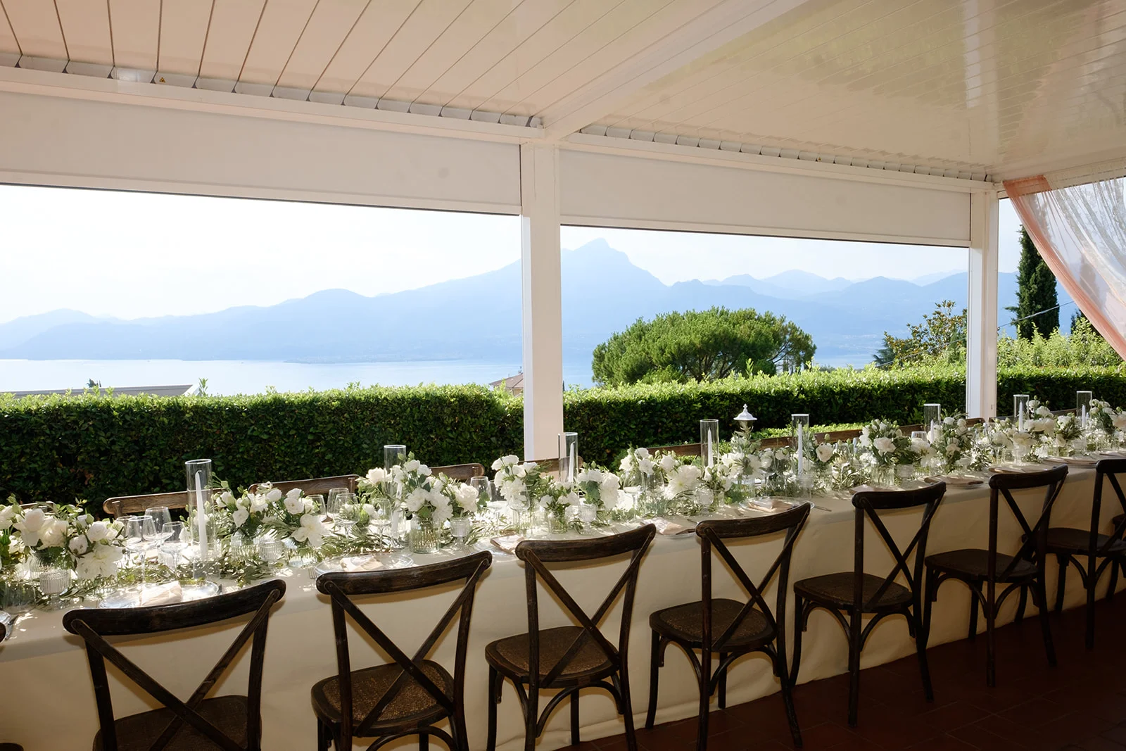 Banchetto matrimoniale con tavoli apparecchiati nella veranda affacciata sul giardino e gli ulivi